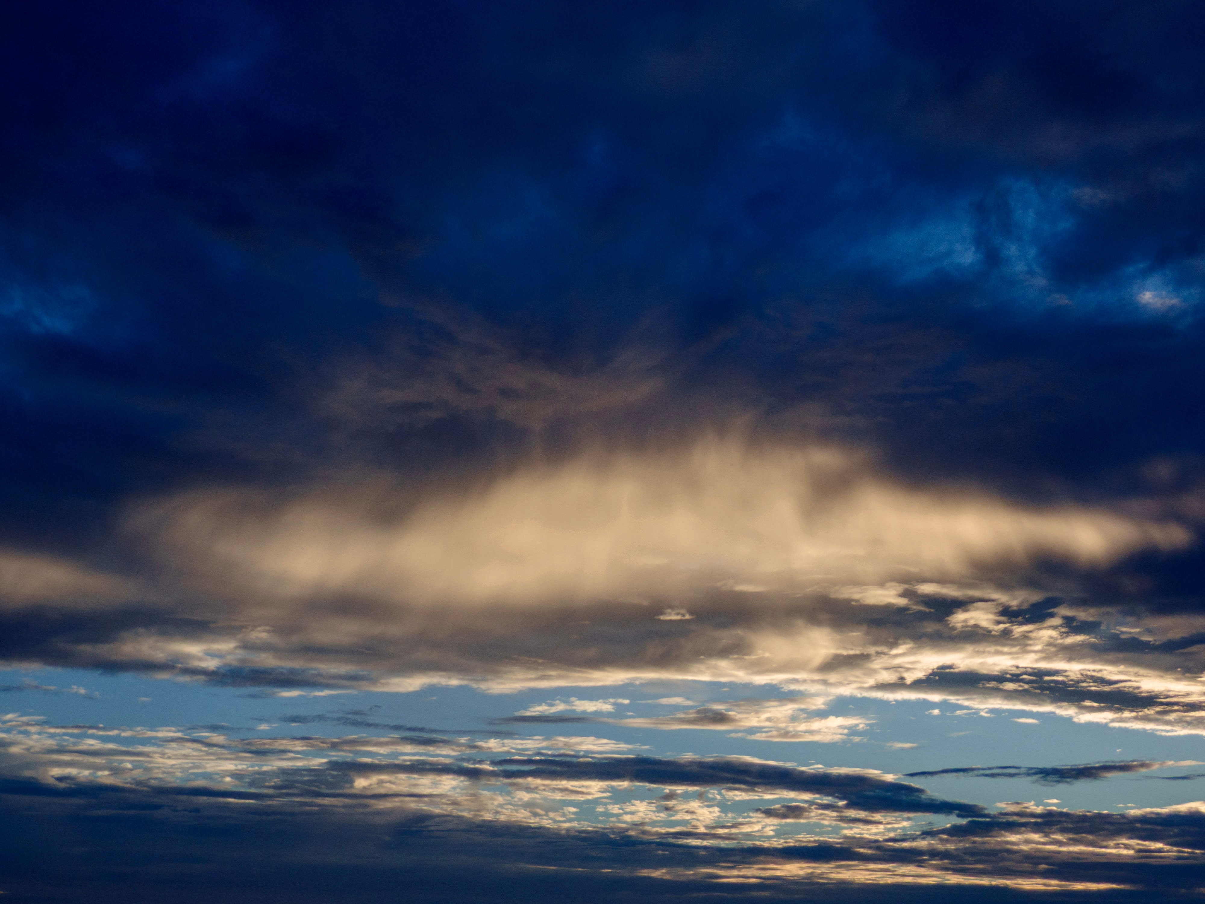 A dark, cloudy sky after sunset with one glowing cloud illuminated from below